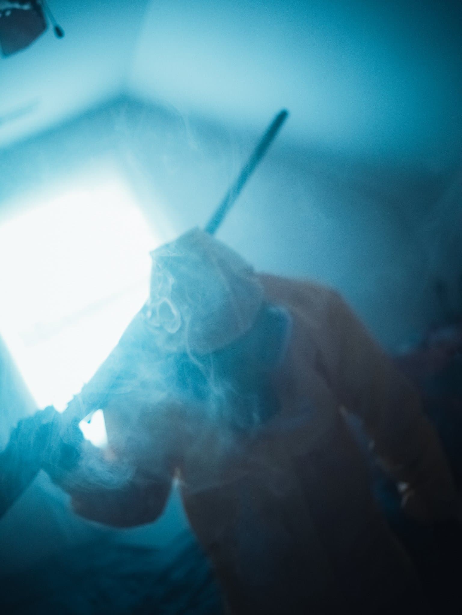 Smoke-wreathed figure in a hazmat suit with a rifle over one shoulder, caught in soft motion blur — human-made reference photo on Slow Sync